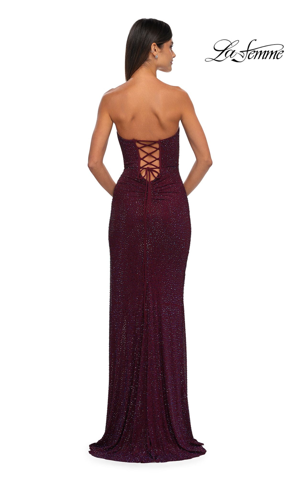 Woman wearing the Strapless Long Glitter Prom Dress: La Femme 32422, a floor-length sparkling burgundy gown with a sweetheart neckline and lace-up back. Shown from behind with the